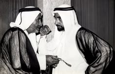 two men dressed in traditional arabic garb talking to each other