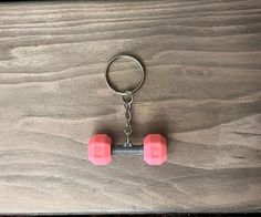 two pink dumbs are on a keychain that is sitting on a wooden surface