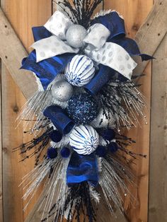 a wreath with blue and silver ornaments hanging on a wooden door