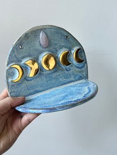 a hand holding a blue and gold plate with phases on it