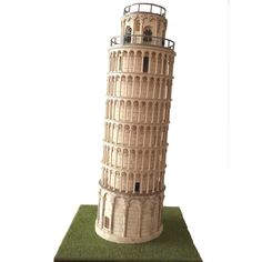 a miniature model of the leaning tower of pisa, with green grass on its base