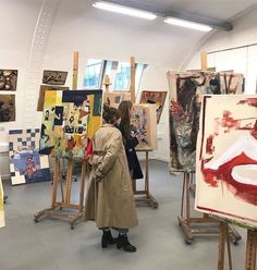 a woman standing in front of paintings on easels