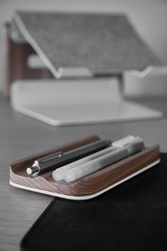 an electronic device sitting on top of a wooden table next to a notebook and pen