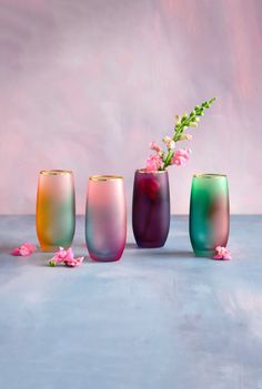 three different colored vases with flowers in them