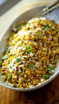 a bowl filled with corn on top of a wooden table