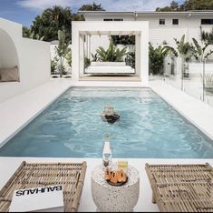 an empty swimming pool with two lounge chairs next to it and a bottle of beer in the middle