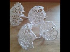 three white crocheted objects sitting on top of a wooden table