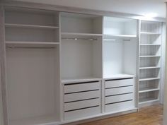 an empty room with white shelves and drawers