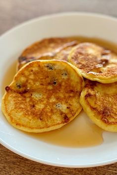 three pancakes on a white plate with syrup