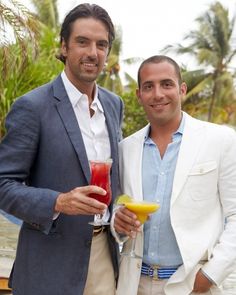 two men standing next to each other holding drinks