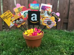 a pot filled with lots of cards and flowers in front of a fenced in area