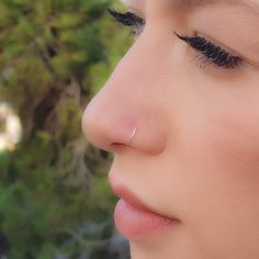 a close up of a woman's face with her nose piercing in the middle