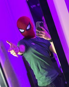 a man taking a selfie in front of a mirror wearing a spiderman mask