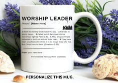 a coffee mug with the words worship leader on it next to some flowers and rocks