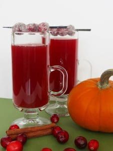 two glasses of cranberry juice next to a pumpkin