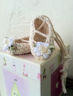 a crocheted baby booties sitting on top of a box next to a wall