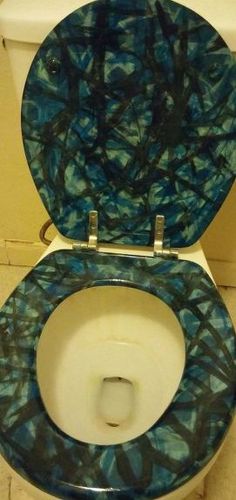 a toilet with blue and green paint on it