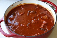 a red pot filled with stew sitting on top of a table