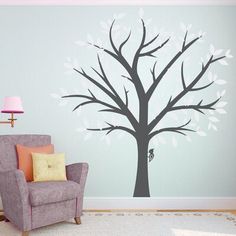 a living room with a chair and wall decal that has a tree on it