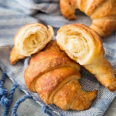 two croissants on a blue and white towel next to some other pastries