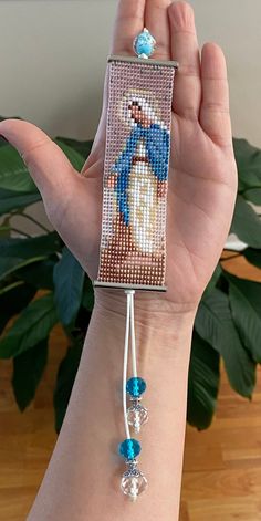 a woman's hand holding a beaded bracelet with an image of a snowman on it