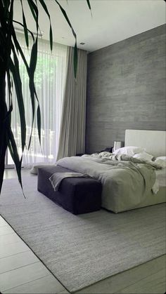 a large bed sitting in the middle of a bedroom next to a tall plant on top of a rug