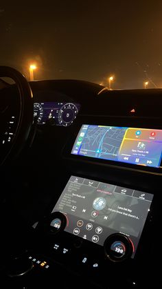 the interior of a car with an electronic display on the dashboard and lights in the background