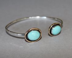 LISTING FOR ONE BANGLE: Two robin's egg blue, natural turquoise gemstones - trimmed with gold - are set on an open-access bangle bracelet of sterling silver. Beautiful worn single or stacked. Avalaible in several gemstone options (see some options on fourth photo) My bangles are made to order and sized to fit - see last photo to measure for your custom fit bangle! Gemstones approx 10-12 / 14mm Silver weight - 12guage Inquire about making this with your favorite gem combo! See all my classic, han Turquoise Cabochon Round Bracelets, Turquoise Round Cabochon Bracelets, Turquoise Cabochon Bracelet, Adjustable Turquoise Cabochon Bracelet, Turquoise Bangle, Cuffs Bracelets, Open Bangle Bracelet, Bracelet Stacking, Robin's Egg Blue