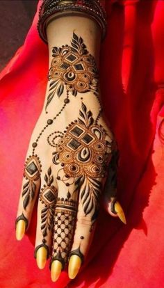 a woman's hand with henna tattoos on it and yellow nails in the middle