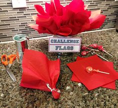 red paper flowers and scissors are on the counter in front of a sign that says challenge flags