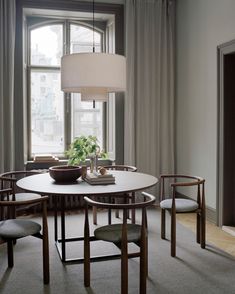 a dining room table with four chairs and a plant in the center, next to a window