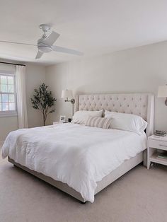 a large white bed sitting in a bedroom next to a window