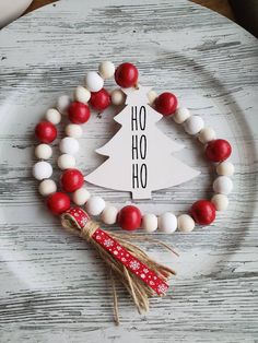 a white plate topped with a red and white beaded christmas tree bracelet on top of a wooden table