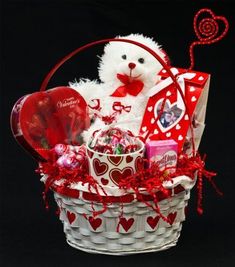 a white teddy bear sitting in a basket filled with valentine's day treats and candy