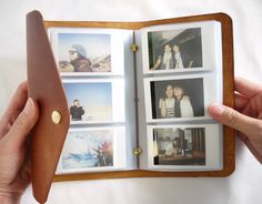 a hand holding an open book with photos on it