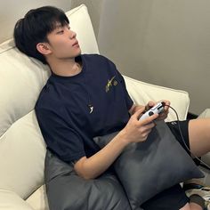 a young man sitting on top of a couch holding a nintendo wii game controller