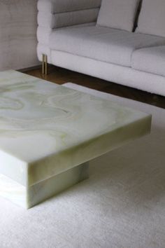 a marble coffee table sitting on top of a white rug in front of a couch