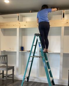 a woman standing on a ladder in front of a book shelf