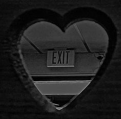 a heart shaped window with the exit sign reflected in it