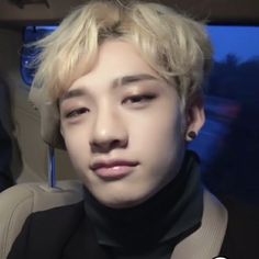 a man with blonde hair sitting in a car looking at the camera while wearing a black turtle neck sweater