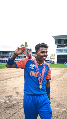 a man holding up a trophy on top of a dirt field