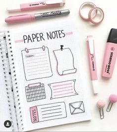 a notebook with paper notes and pink pens on it next to some other items that are laying around