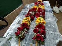 two rows of red and yellow roses on top of a newspaper with baby's breath