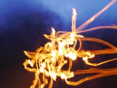 blurry photograph of fire with blue sky in background