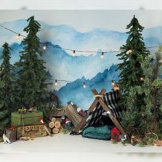 there are many christmas trees and presents in front of the mountain backdrop that is painted with watercolors