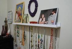 there is a white shelf with many necklaces hanging on it and a couple holding each other