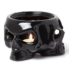 a black skull shaped candle holder with a lit candle in it's eyeballs