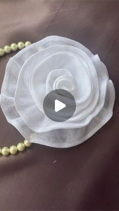 a white flower and pearls necklace on a brown cloth with the words, how to make beaded flowers