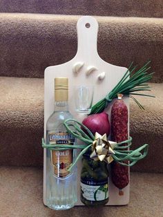 an assortment of food and drinks on a wooden cutting board sitting on the stairs next to some wine bottles