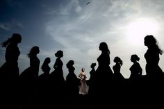 a group of women standing next to each other in front of a sky with clouds